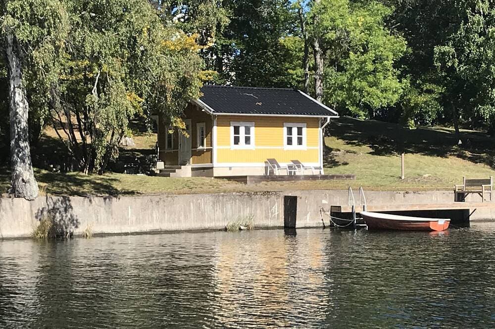 Cottage mit sonnigem Holzdeck am Wasser. 1